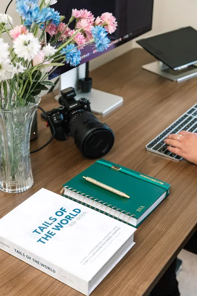 A camera, notebook and flowers arranged on the desk of pet photography business coach Ina J